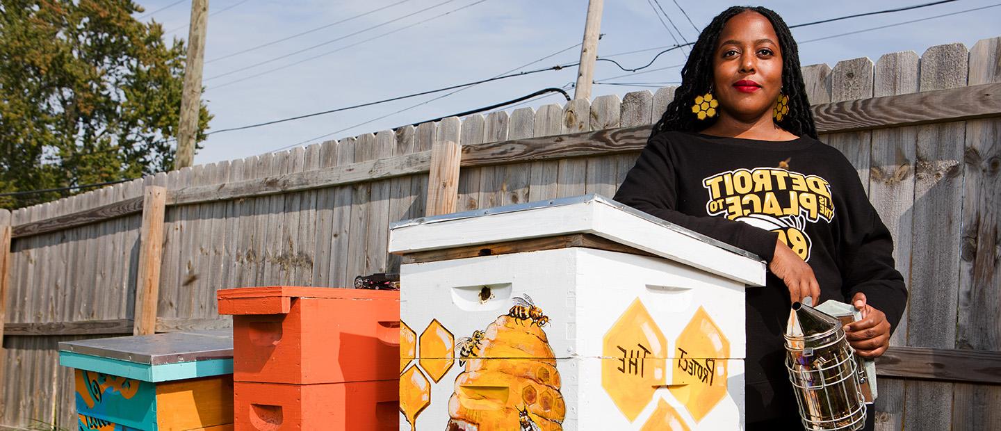 An OU alumni standing next to bee boxes.